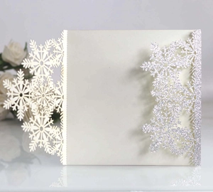Intricate laser-cut snowflake detail with silver glitter on white invitation card