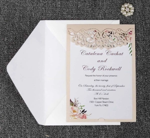 Intricate laser-cut lace pattern detail on champagne wedding invitation cover with insert