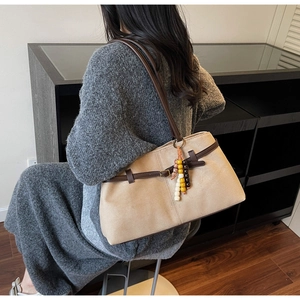 Detail of beige suede tote bag with dark brown leather straps and colorful beaded tassel