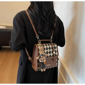 Detail view of rhombic pattern backpack featuring a plush rabbit pendant and leather trim