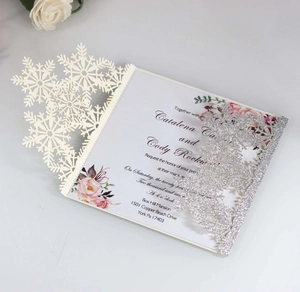 Macro shot of silver laser-cut snowflake wedding invitation with elegant pink floral card