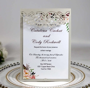 Close-up of laser-cut lace champagne invitation sleeve with floral inner wedding card