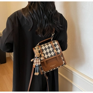 Detail of vintage quilted crossbody bag with plaid bunny charm and gold lock buckle