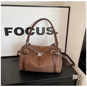 Macro shot of dark brown suede boston bag with silver hardware and smooth leather straps