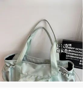 Detail of mint green nylon travel tote with quilted pocket and sturdy handle