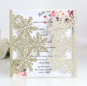 Detail of laser-cut gold glitter snowflake cover with floral wedding invitation insert