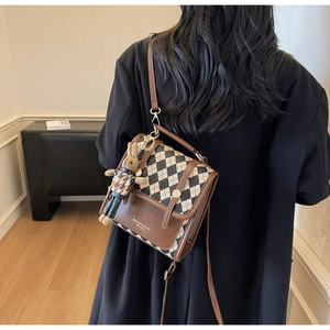 Detailed view of checkered crossbody bag with vintage brown trim and a cute rabbit charm