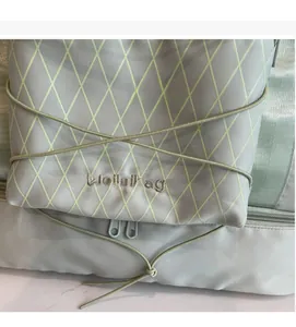 Detail of light gray travel bag with green mesh, elastic cords and Weilailbag logo