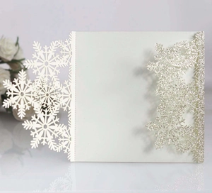 Detail of laser-cut white snowflake invitation card with silver glitter finish for Christmas