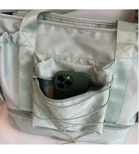 Front zipper pocket of a green travel bag showing capacity for a large smartphone