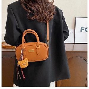 Caramel retro bowling bag with gold hardware and a cute teddy bear charm on a crossbody strap