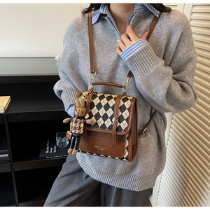 Detail of vintage checkerboard crossbody bag with leather trim and rabbit charm