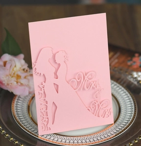 Détail de l'invitation de mariage rose découpée au laser avec texte Mrs & Mrs et silhouettes