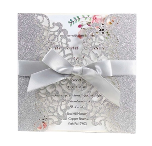 Détail d'invitation de mariage découpée au laser avec paillettes argent et ruban