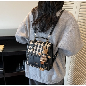 Close-up of black and white lattice backpack with PU leather flap and brown bunny charm