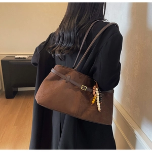 Brown suede tote bag worn by a model in a black blazer showing spacious capacity