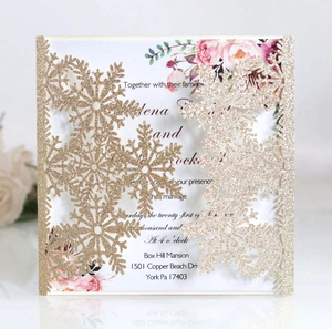 Macro detail of laser-cut glitter snowflake invitation with elegant floral inner card