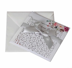 Détail d'invitation de mariage découpée au laser avec motifs floraux et ruban argenté