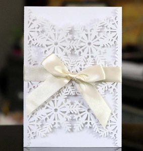 Gros plan d'un motif de flocon de neige découpé au laser sur carte blanche avec ruban