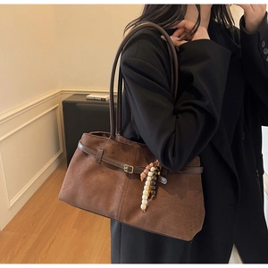 Detail of vintage brown suede tote bag with stylish buckle strap and bead charm accessory