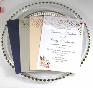 Detailed laser-cut wedding invitations in four colors on a decorative glass tray