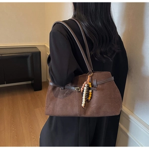 Detail view of brown suede tote bag with beaded pendant and slim shoulder strap