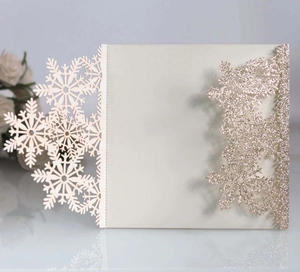 Macro view of laser-cut snowflake patterns on pearlescent white wedding invitation cards
