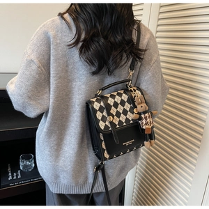 Detail of crossbody bag with beige rhombus pattern and a cute rabbit doll charm