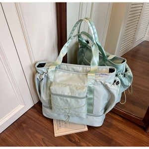 Detail of mint green travel duffel bag with quilted front pocket and shoe compartment