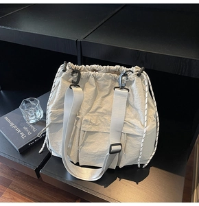 Detail of off-white nylon drawstring bucket bag with adjustable wide strap on shelf