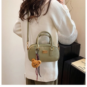 Detailed back view of a bean green handbag with cute bear charm and gold metal plaque