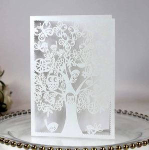 Detail of laser-cut white greeting card showing intricate forest patterns on a glass plate