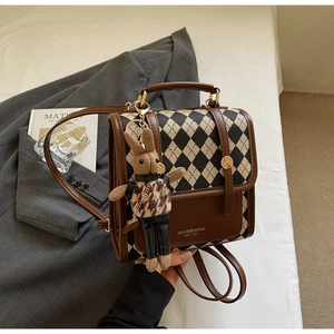 Detailed view of vintage quilted patchwork backpack with knit rabbit charm on a white bed