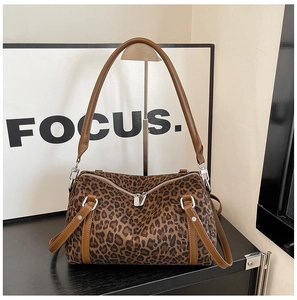 Detail view of leopard print texture with brown leather handles and silver zipper