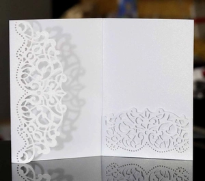 Detail of laser-cut lace pattern on white pearlescent paper wedding invitation