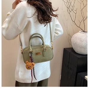 Detail of light green matte leather handbag with golden logo and plush bear charm