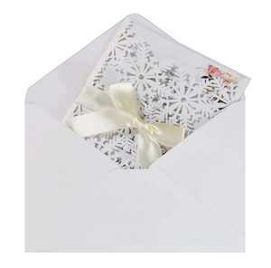 Détail d'invitation flocon de neige découpée au laser avec nœud crème et enveloppe blanche