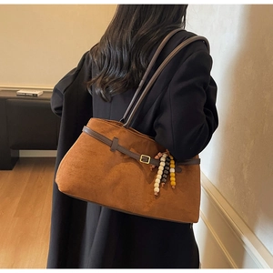 Close-up of brown suede shoulder bag with decorative colorful beads and metallic buckle