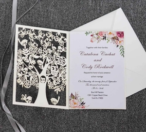 Macro detail of laser-cut tree and owl design on white wedding invitation card