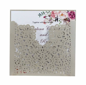 Détail de l'invitation de mariage dorée découpée au laser avec des motifs floraux fins