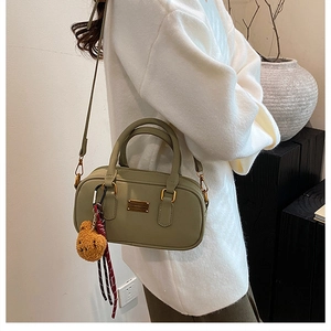 Detail view of olive green mini bowling bag with cute brown bear charm and gold plaque