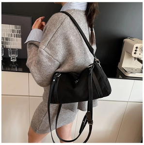 Chic black minimalist crossbody bag shown in a stylish home setting with model