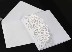 Detailed laser-cut lace pattern on elegant white wedding invitation card with envelope