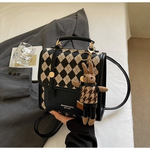 Detail of checkered shoulder bag with gold logo and cute plaid rabbit pendant