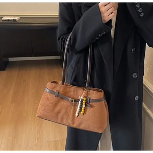 Detail of vintage brown suede tote bag featuring leather straps and colorful beaded charm