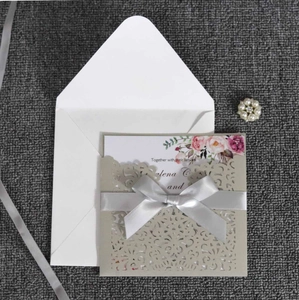 Détail d'invitation de mariage découpée au laser avec pochette crème et ruban satin