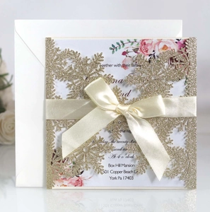 Golden glitter snowflake laser cut wedding invitation with cream ribbon and white envelope