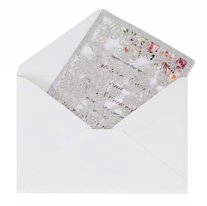 Detail of silver glitter laser-cut wedding invitation with intricate tree and bird design