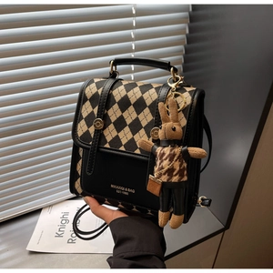 Detail of vintage checkerboard crossbody bag with a small woven rabbit doll pendant