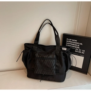 Detail of black waterproof nylon travel bag with quilted front pocket and drawstring sides